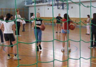 Students with basketballs seen from behind the net